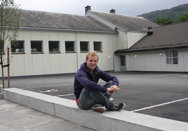 Person sitter på betongmurkant. Foto.
