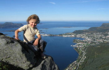 Jente sittende på stor stein, utsikt over Ulsteinvik. Foto