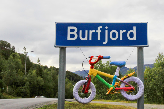 Barnesykkel som henger fra Burfjord-skilt. Foto.