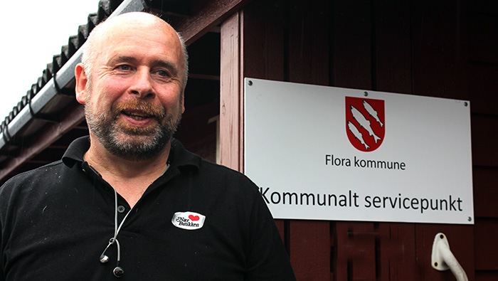 Mann framfor skilt: "Flora kommune Kommunalt servicepunkt". Foto.