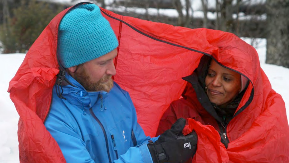 To personer inni en rød teltduk. Foto.